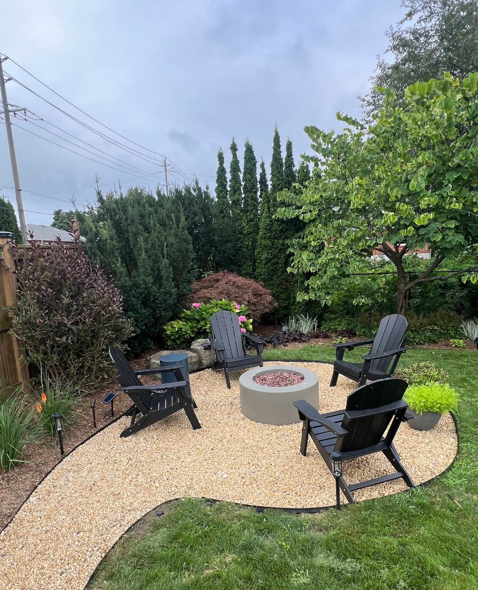 Backyard fire pit installation with Adirondack chairs, pea gravel patio and mature garden beds